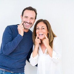 man and woman pointing to their smiles