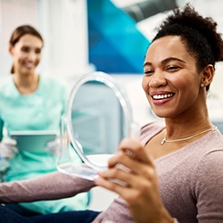 Woman looking at reflection in mirror at dentist's office