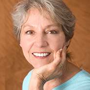 Older woman smiling and touching her face