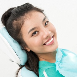 A young female lying back in a dentist’s chair waiting to receive a dental checkup and cleaning