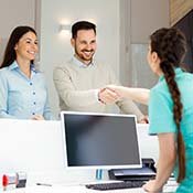 dental team member shaking a patient’s hand over the front desk 