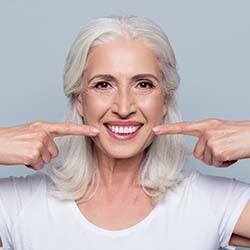 senior woman pointing to her smile 