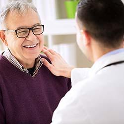 dental implant dentist in Louisville placing their hand on a patient’s shoulder 