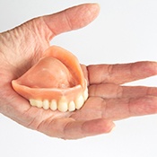 Outstretched hand holding upper arch dentures 