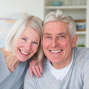 Senior man and woman smiling in gray sweaters