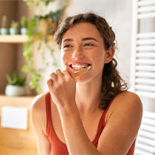 a woman brushing teeth for dental implant care in Louisville