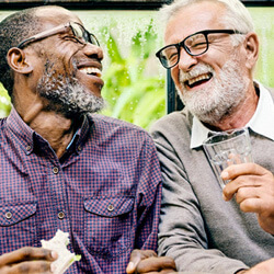 older patient talking with a friend in Louisville with his implant dentures