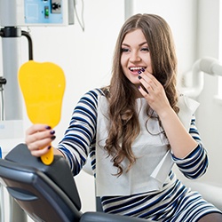 Woman looking at her smile in a dental mirror.