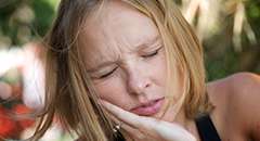 woman holding cheek in pain