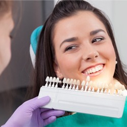 A dentist comparing ceramic shades to a patient’s teeth.