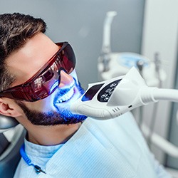 a man sitting in a dental chair having his teeth whitened