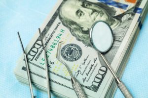 Dental tools on top of $100 bills for dental insurance