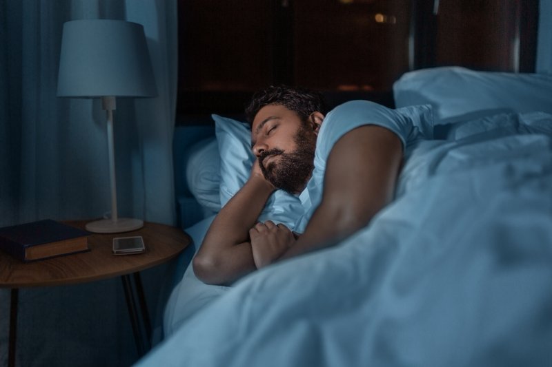 Man with bruxism and dental implants asleep in bed