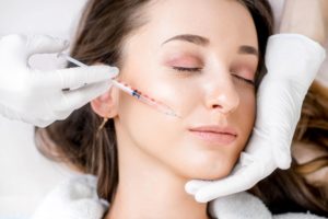 View of woman's face with eyes closed while white gloved hands inject BOTOX