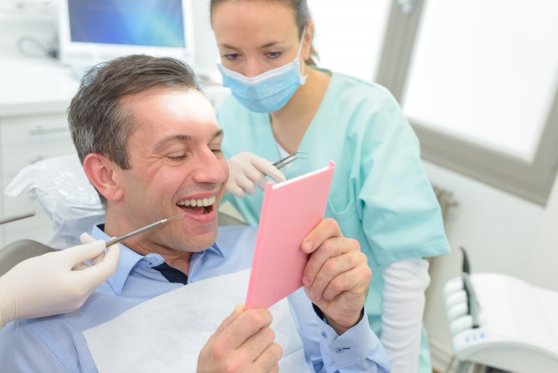 A man smiling at the dentist after getting his new dental implants