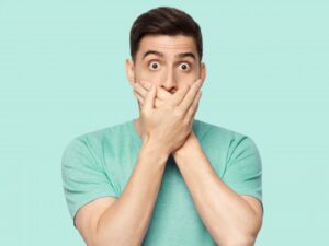 Man covering mouth after losing dental bridge