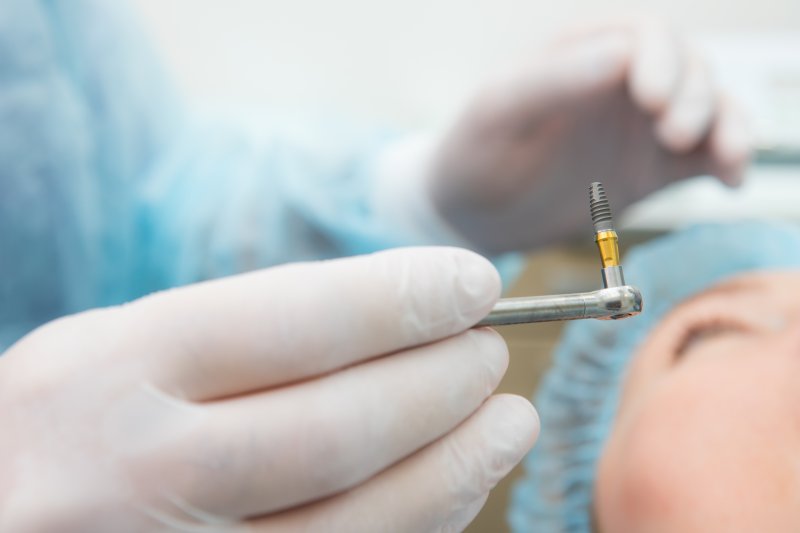 A dental implant post held by a gloved hand