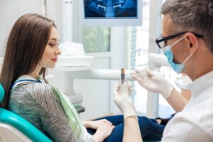 Dentist explaining dental implant to patient. 