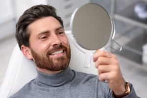 Man smiling into mirror after cosmetic dentistry