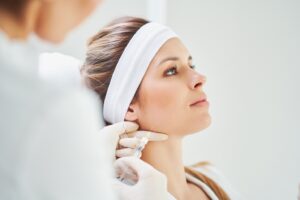 Woman wearing white headband receiving BOTOX injection in her jaw.